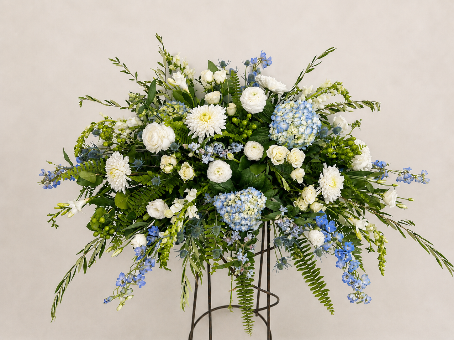 Blue Skies of Remembrance blue and white casket spray with hydrangea, roses, white blooms and lush garden-inspired greenery