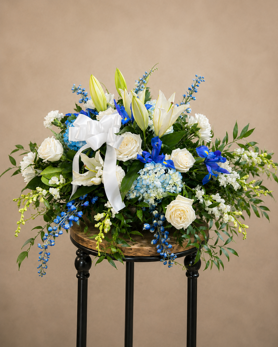 Blue and white open casket spray with roses, hydrangea, lilies and garden-inspired greenery