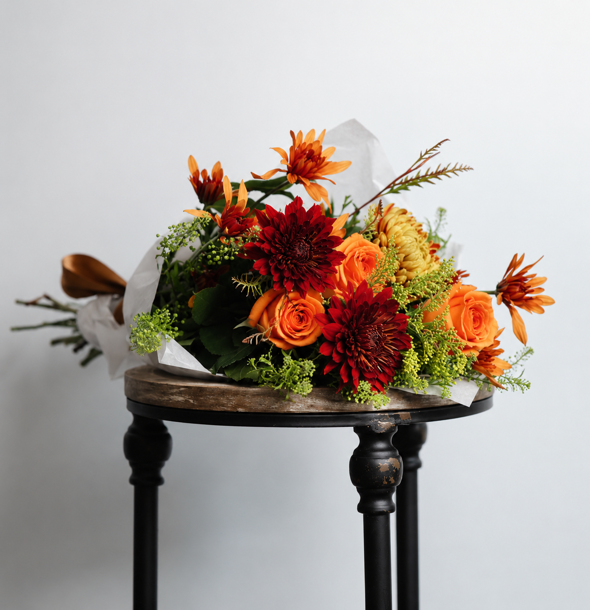 Golden Harvest wrapped fall bouquet featuring orange roses, bronze chrysanthemums, yellow asters, eucalyptus, and grevillea wrapped in parchment paper.

Shopify Tags