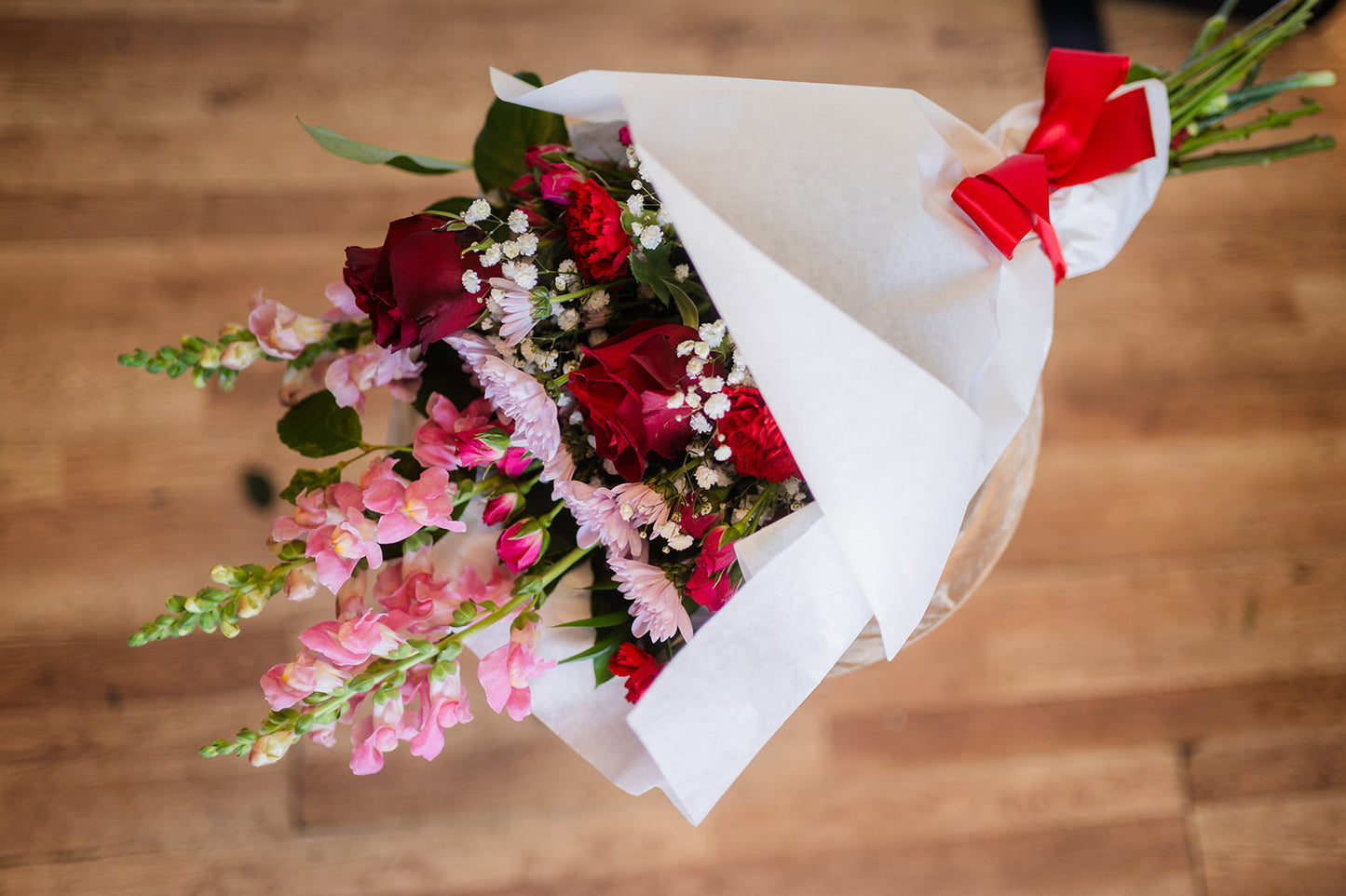Bouquet of flowers with red and pink colors on a wooden surface