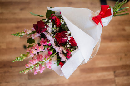 Bouquet of flowers with red and pink colors on a wooden surface