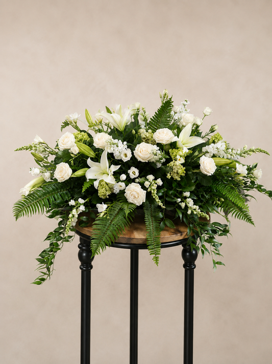 Sincere Sympathy white and green casket spray with roses, lilies, hydrangea, delicate white blooms and lush cascading greenery.