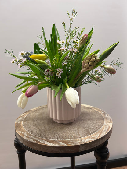 Floral arrangement on a decorative stand against a plain background